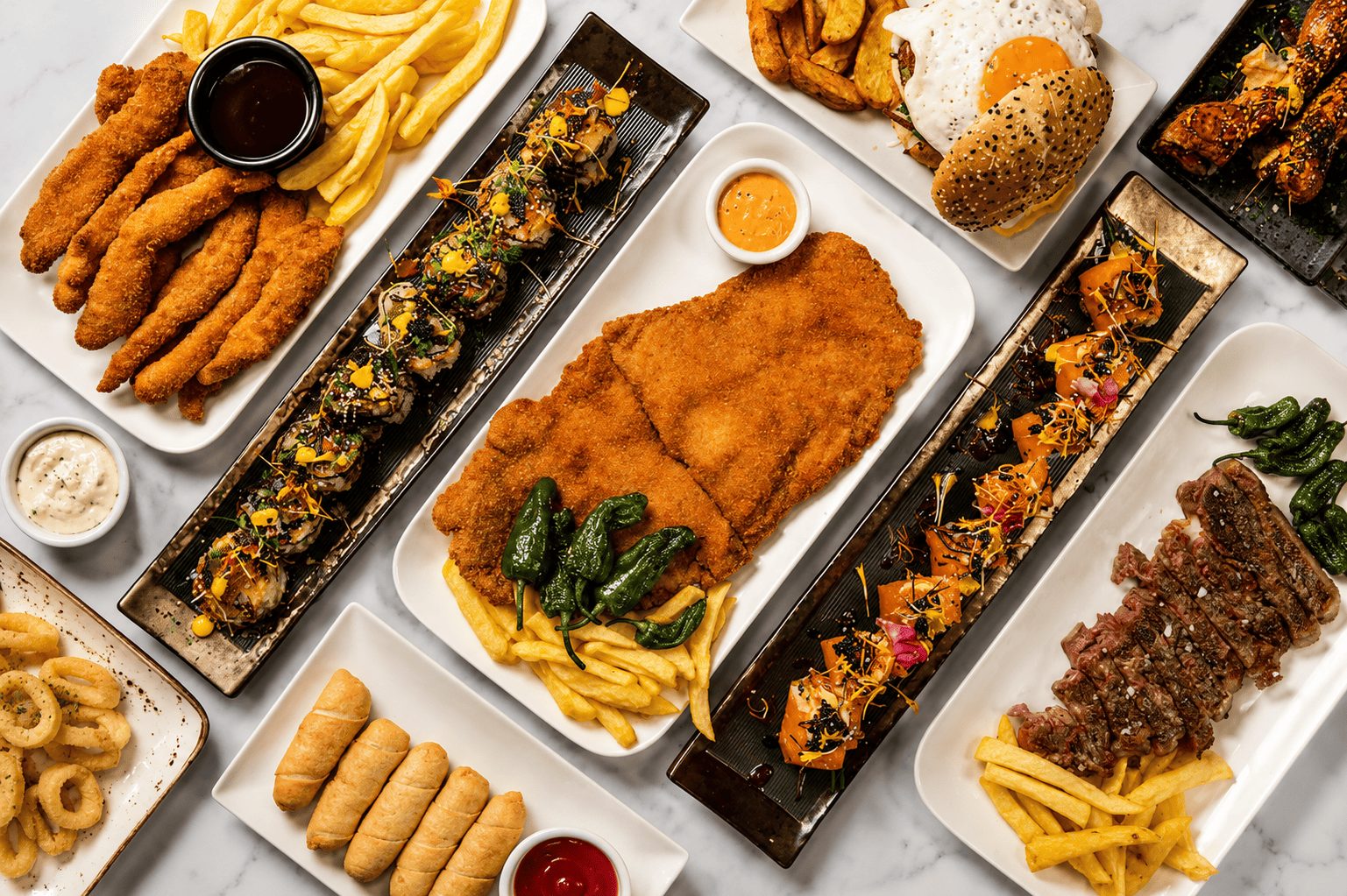 Mesa con varias raciones de Donde Dani: cachopo, bravas, makis, entrecot y patatas